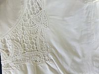 Close-up of embroidered leaf and honeycomb cutwork on white cotton