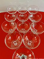 Top view of 11 clear coupe glasses arranged showing bowls and faceted stems