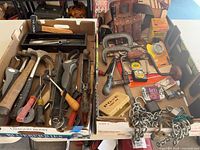 overview of two boxes containing assorted hand tools and hardware