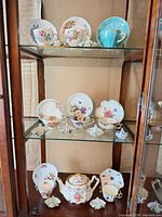 Display cabinet showing all teacups, saucers and teapot