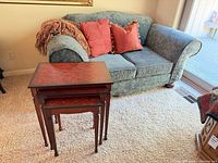 Loveseat with throw pillows, blanket, and nested tables