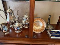 Full set displayed in cabinet: coffee pot, teapot, sugar bowl with lid, creamer, serving bowl, candlestick, four knives