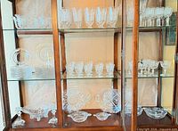 Cabinet view showing assorted etched stemware, plates and serving dishes