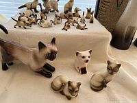 Group of assorted size Howard Pierce cat figurines on cloth background