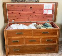 Chest open showing cedar interior, paperwork, decorative drawer fronts, functional bottom drawer
