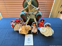 Group shot of all dolls, cloth cat, and booklet on table