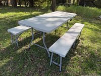 Assembled light grey resin folding table with two matching benches outdoors