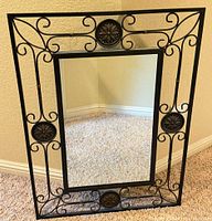 Full view of black metal ornate mirror with scrollwork frame