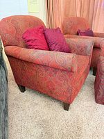 Two red paisley upholstered armchairs with accent pillows