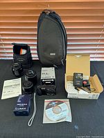 Group shot of camera, lenses, boxes, battery, CD, manuals, Kodak case, ThinkTank sling backpack