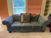 Front view of upholstered sofa with pillow and throw
