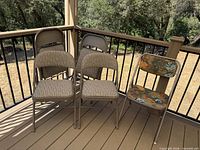 Five Samsonite folding chairs on deck, showing four matching beige striped chairs and one floral chair