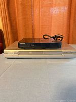 Samsung Blu-Ray player resting atop LiteOn DVD recorder on table