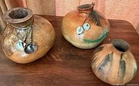 Three gourd vases on wooden surface showing size and decorative elements