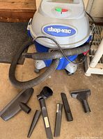 Vacuum canister with hose and six accessories on floor