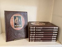 Front cover of one book and stacked spines of remaining seven