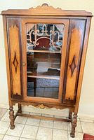 Front view of inlaid wood curio cabinet showing glass door and decorative inlay