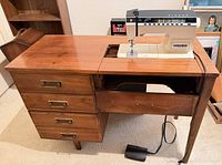 Singer sewing machine installed in cabinet, drawers visible