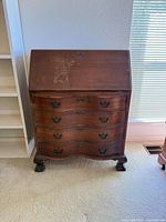 Front view of closed secretary desk showing serpentine drawers and claw feet