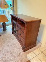 Three-quarter side view of media console showing wood finish, open compartments and side profile