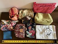 Full group of nine assorted fabric cosmetic bags and coin purse with ruler for scale