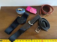 Top view showing all six belts laid out with measuring tape for scale