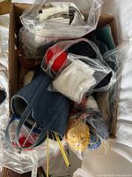 Overview of box with denim tote, yarn, lace trim, needles