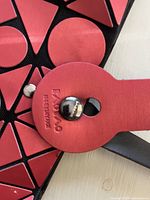 Close-up of connector and geometric red panels with embossed Bao Bao Issey Miyake text