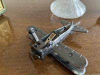 Underside of cast metal biplane, perfume bottle partially visible