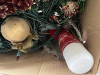 Boxed lot showing light strings, wreath greenery, ornament and snow spray can