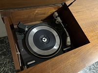 Overhead view of turntable inside left compartment showing platter, tonearm and cartridge