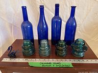 four cobalt blue bottles, three aqua insulators, cobalt swan figurine displayed with ruler