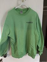 Front view of lime green crewneck sweatshirt showing chest logo and overall condition