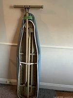 Ironing board folded showing underside wooden board and metal frame