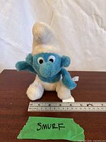 Front view of Ganz Smurf plush with ruler showing size
