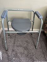 Front view of gray metal frame bedside commode with lid closed