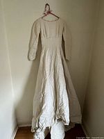 Front view of full-length ivory brocade wedding dress hanging