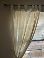 Curtain panel hanging from rod showing tab top and sheer fabric