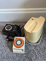 Front view of all three items showing Time-All timer, black timer, cream appliance