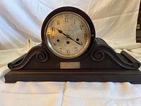 Front view of wooden mantel clock showing full case and dial