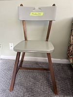 Front view of chair showing painted seat/backrest and wood frame