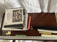 Stack of Christmas music CDs, tealights in plastic holder, taper candles on wooden surface