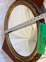 Front view showing full oval mirror and ornate frame