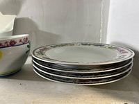 Stack of four rimmed soup/pasta bowls showing floral border pattern
