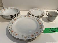 Stack of bowls, plates and single mug showing floral pattern and gold rim