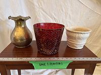 Full view of brass vase, red mosaic glass planter, white ceramic planter on table