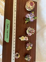Top view of all eight floral figurines with ruler for scale