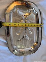Top view of silver-plate over copper serving tray with tape showing width ~9.5 in; visible scratches and tarnish