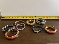 All eight bracelets arranged for overview with tape for scale