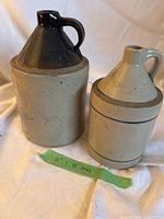 Two stoneware jugs side by side on cloth backdrop